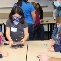 Young visitors work on a solar car in a group